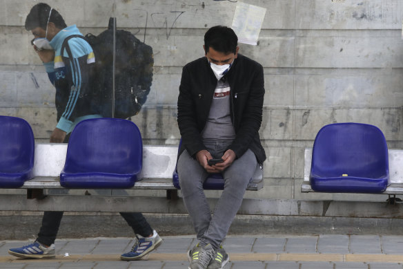 A man waits at a bus stop in Niavaran, northern Tehran, where officials have begun easing the lockdown.