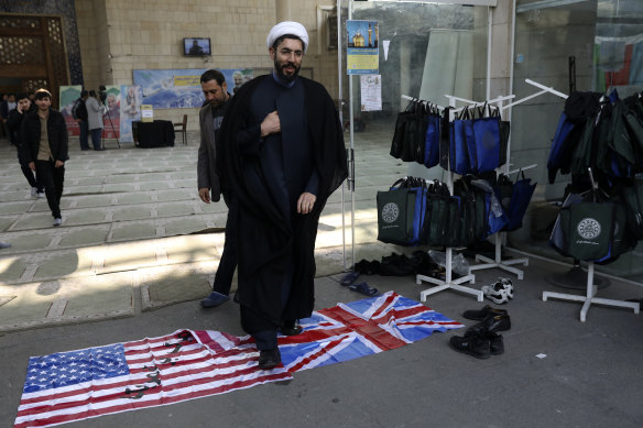 A cleric walks on the US and British flags while leaving a gathering to commemorate the late Iranian General Qassem Soleimani, who was killed in a US drone attack on January 3.