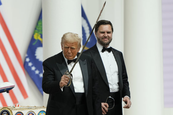 Donald Trump holds a sabre after using it to cut a cake, as Vice President J.D. Vance looks on, at the Commander-in-Chief Inaugural Ball.