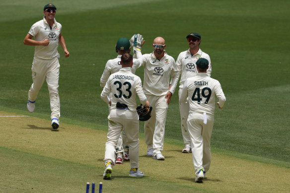Nathan Lyon celebrates with teammates after taking the wicket of Imam-ul-Haq on day three in Perth.