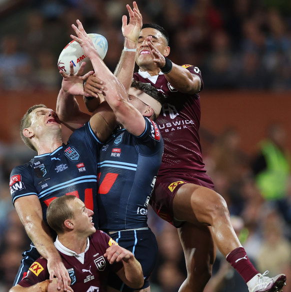 Valentine Holmes of the Maroons and Tom Trbojevic of the Blues compete for the ball in the air during game one of the 2023 State of Origin series.