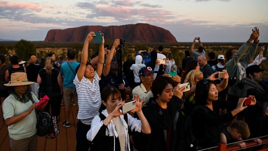 Tourists taking photographs of the rising sun near Uluru on October 12. 