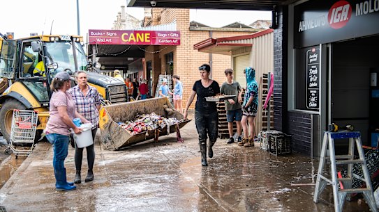 Shop owners try to clean up after floodwaters in Molong, NSW. 14th November 2022. Photo by Monique Lovick / Sydney Morning Herald.