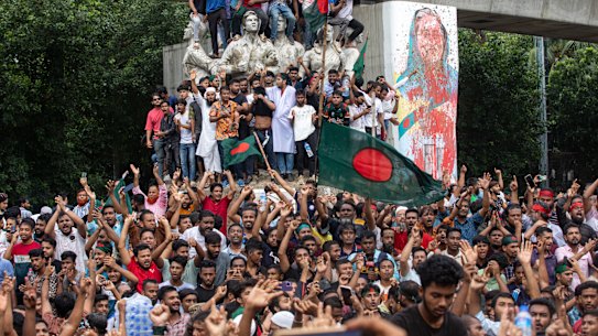 Protesters climb a public monument in Dhaka as they celebrate the news of Prime Minister Sheikh Hasina’s resignation.