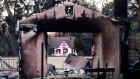 A home destroyed by the Eaton Fire stands in front of a home that survived in Altadena. 
