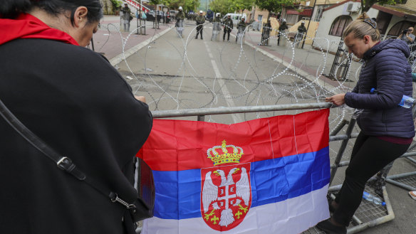 Women attach a Serbian flag to a fence in front of the city hall during a protest in the town of Zvecan, northern Kosovo, on Wednesday. Hundreds of ethnic Serbs gathered at the city hall to try and take over the offices of one of the municipalities where ethnic Albanian mayors took up their posts last week.