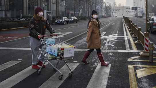 A Chinese couple walk with their groceries in a nearly empty street in Beijing. The caronavirus has hit demand for Australian company's products. 