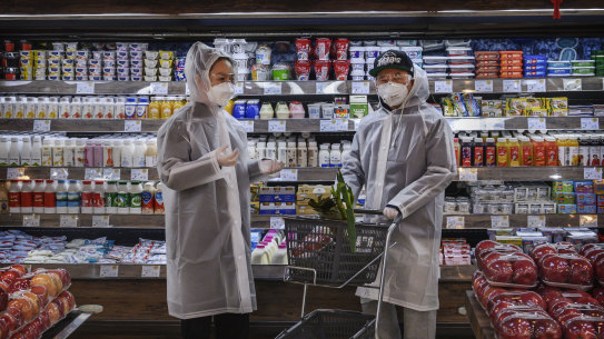 Beijing residents wear protective clothing as they shop for groceries.
