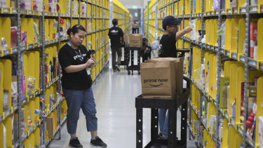 Staff collect merchandise for customers' orders from shelves at the newly-opened Amazon Prime Now facility in Singapore. 