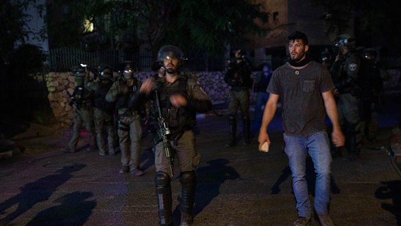 Jewish right-wing demonstrator holds a rock as he stand by Israeli paramilitary border police during clashes between Arabs, police and Jews, in the mixed town of Lod, central Israel.