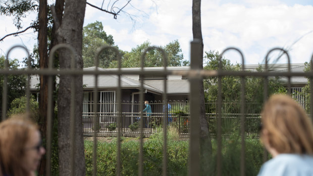 Joyce Parker and Mary Watson wave to their mother, Alice Bacon, from outside the Newmarch House fence on Wednesday. 