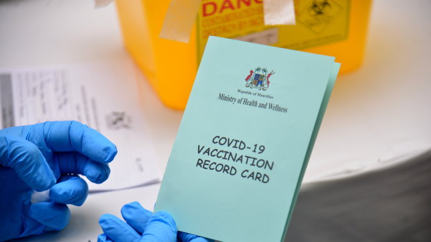 A nurse holds a copy of a COVID-19 vaccination card to be given to people who receive the AstraZeneca vaccine in a vaccination center set in a tourist resort north of Port Louis, Mauritius.