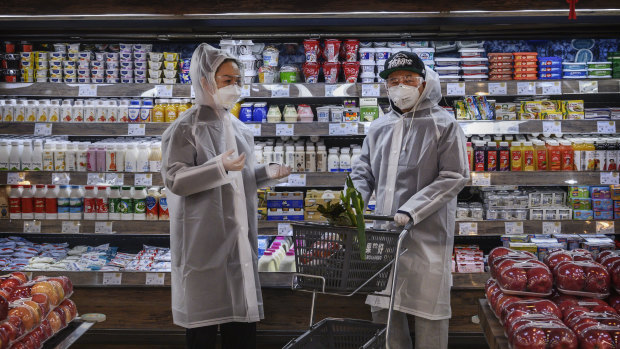 Beijing residents wear protective clothing as they shop for groceries.