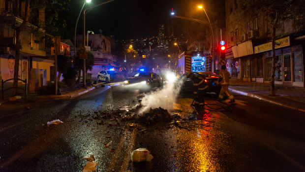 Firefighters extinguish a fire lit by rioters in Haifa, Israel.
