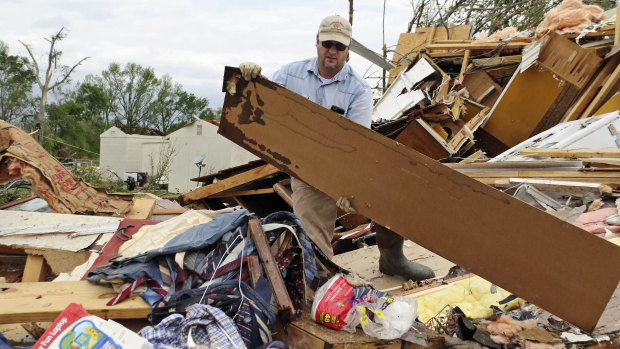 Roman Brown moves part of a wall out of his way in a friend's destroyed home outside of Hamilton, Mississippi, on Sunday.
