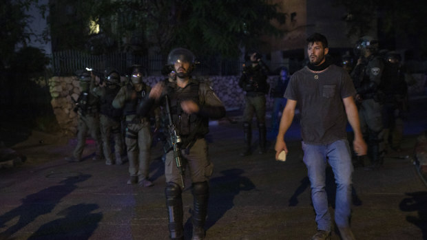 Jewish right-wing demonstrator holds a rock as he stand by Israeli paramilitary border police during clashes between Arabs, police and Jews, in the mixed town of Lod, central Israel.