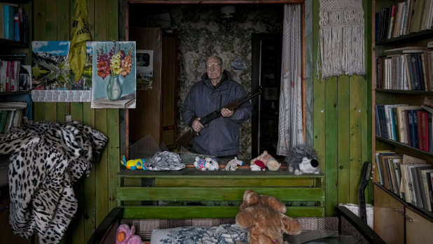 French teacher Pjotr Vyerko, 81, holds a rifle standing behind the broken window of a bedroom in his house which was damaged by the shock waves of a Russian airstrike in Gorenka, outside the capital Kyiv.