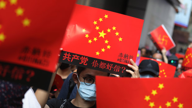 Demonstrators holding signs featuring a swastika made up of yellow stars against a red background march along Hennessy Road during a protest in the Causeway Bay district of Hong Kong.