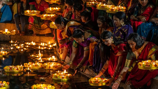 Women light oil lamps for Diwali in Mumbai.
