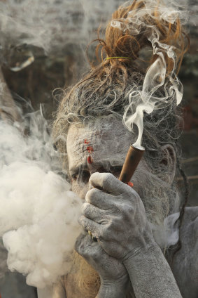 A naga sahu, or Hindu naked holy man, smokes before proceeding towards the Sangam in early January, as part of celebrations for the 45-day festival.