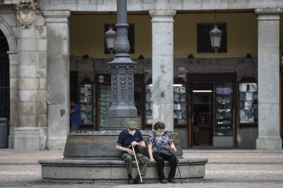 A man and woman sit in downtown Madrid, which is experiencing a surge in coronavirus infections.