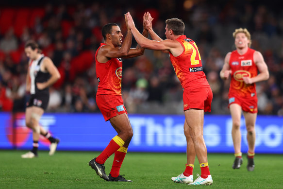 Touk Miller of the Suns (L) congratulates David Swallow of the Suns (C) after he kicked a goal.