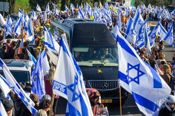 Thousands of people line the entrance to the Ayalon highway to watch and pay their respects as the funeral procession carrying the caskets of Shiri, Kfir and Ariel Bibas pass by with the family in minibuses behind them.