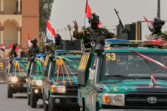 Iraqi security officers flash victory signs as they celebrate the complete withdrawal of US troops.