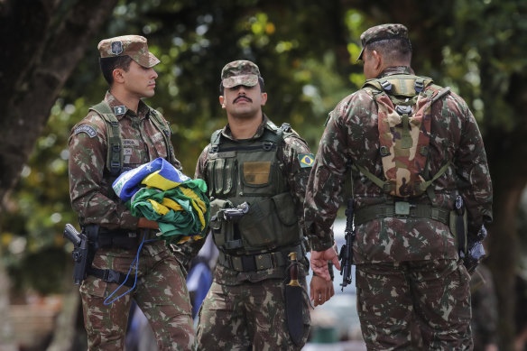 A soldier carefully collects national flags after supporters of former Brazilian president Jair Bolsonaro left the encampment.