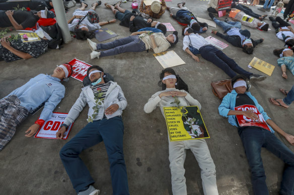 Young demonstrators, with their eyes blindfolded, lie down in the street on Tuesday in Yangon.  