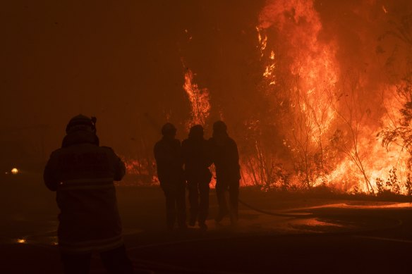 A firefighter is assisted seconds after being hit in thick smoke as fire roared through Eastern Bilpin. 