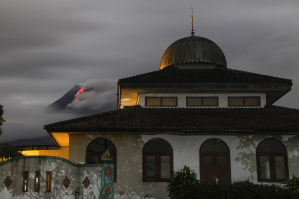Hot lava runs down from the crater of Mount Merapi, partially seen behind a mosque in Sleman, Indonesia.