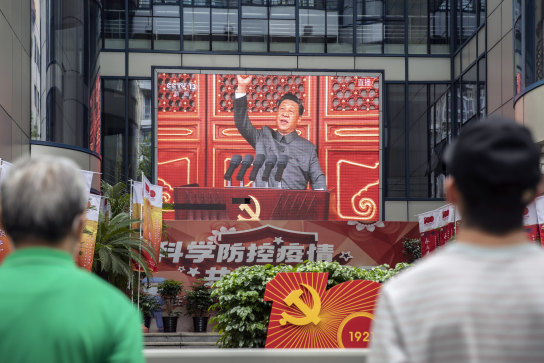 Pedestrians watch a screen showing a live news broadcast of Chinese President Xi Jinping speaking at a ceremony marking the centenary of the Chinese Community Party on Thursday.