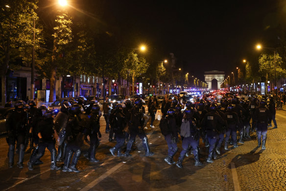 Police officers on the Champs-Elysees in Paris on Saturday during riots following the death of Nahel Merzouk, a 17-year-old teenager killed by a French police officer in Nanterre during a traffic stop.