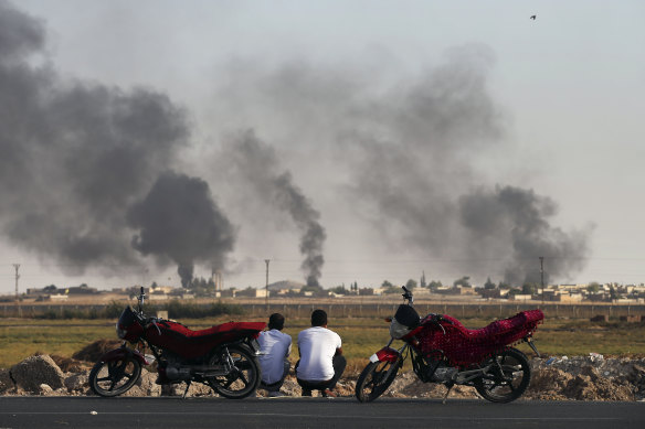 People in Akcakale Sanliurfa province, south-eastern Turkey, watch smoke billowing inside Syria.