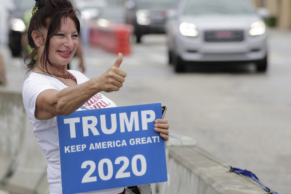 A supporter gives a thumbs-up as she waits to see the motorcade carrying US President Donald Trump pass by on his way to Mar-a-Largo.