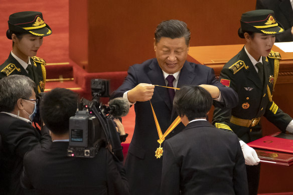 Chinese President Xi Jinping presents a medal at an event to honour some of those involved in the fight against COVID-19 at the Great Hall of the People in Beijing on Tuesday.