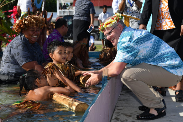 Children symbolically representing climate change greet Prime Minister Scott Morrison as he arrives for the Pacific Islands Forum in Tuvalu.