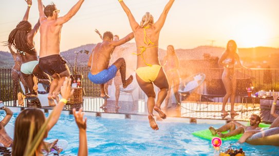 Young people in bikini and swimming shorts jumping in the pool on pool party, shot in maid-air. Photo iStock
