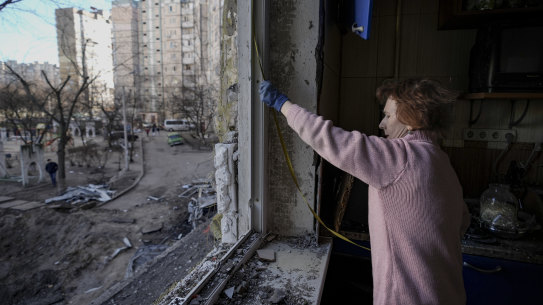 A woman measures a window before covering it with plastic sheets in a building damaged by a bombing the previous day in Kyiv, Ukraine.