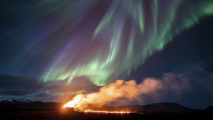 A view of the eruption area with the northern lights dancing in the sky near the town of Grindavik, Iceland.
