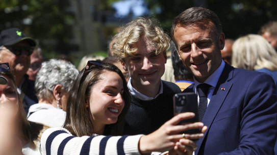French President Emmanuel Macron poses for pictures outside a polling station during the European election, in northern France.