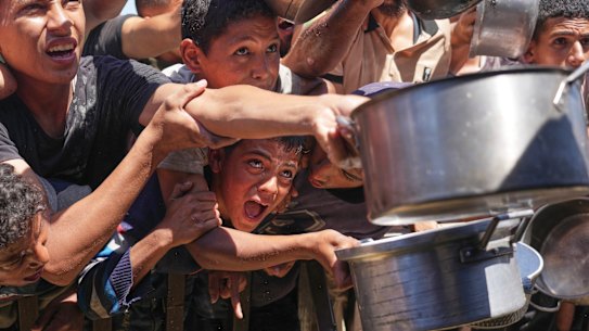 Palestinians attempt to get food at a community kitchen in Khan Younis, in the Gaza Strip, on May 23.