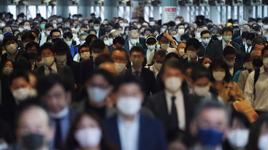 A station passageway is crowded with commuters wearing face masks to help curb the spread of the coronavirus during a rush hour in Tokyo. 