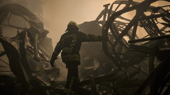 A Ukrainian firefighter walks through the remains of a food storage facility on the outskirts of Kyiv. 