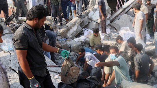 A man holds a children's backpack as rescuers and residents search the rubble following an Israeli-US attack on a girls' primary school in Minab, Iran, Iranian authorities say.
