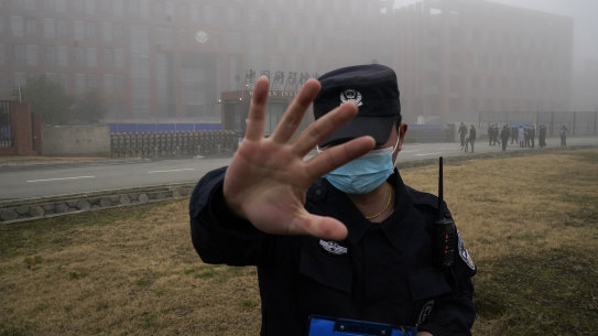 A security guard moves journalists away from the Wuhan Institute of Virology as the WHO team arrives for a field visit in February.