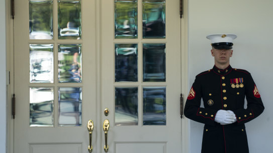 A Marine is posted outside the West Wing of the White House, signifying the President is in the Oval Office.
