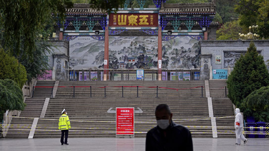 A worker stands at the entrance to Wuquan Mountain which is closed to prevent visitors gathering in Lanzhou city in Gasu province, north-west China, on Monday.