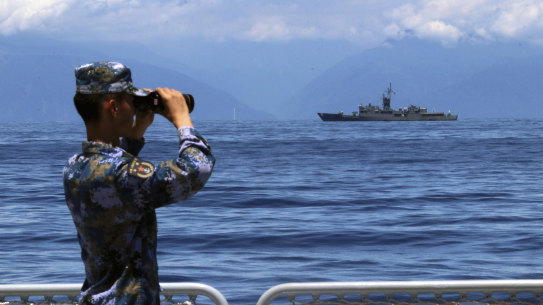 A People’s Liberation Army member watches military exercises, with Taiwan’s frigate Lan Yang in the background.